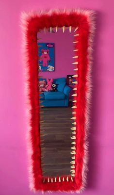 a mirror that has some kind of red thing on it's face in front of a pink wall