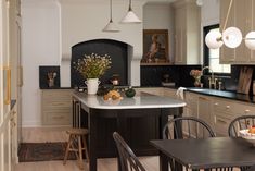 a large kitchen with an island in the middle and chairs at the table, along with two lamps hanging from the ceiling