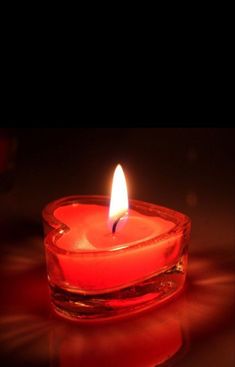 a lit candle sitting in a glass bowl