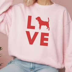 a woman wearing a pink love sweatshirt with a dog on it