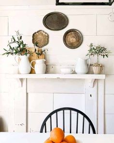 a white table topped with oranges next to a fireplace