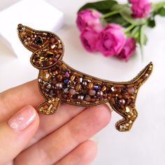 a person holding a beaded dachshund brooch