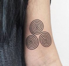 a black and white photo of a tattoo design on the left inner arm, with three spirals at the center