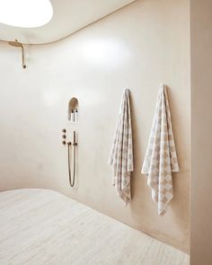 two white towels hanging on the wall next to a shower head and hand towel rack