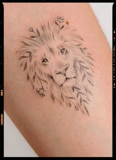 a lion tattoo on the back of a woman's arm, with leaves around it