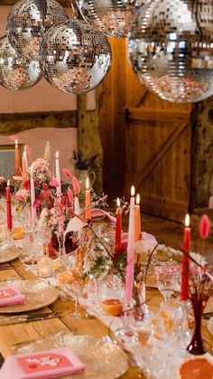 an image of a table setting with disco balls hanging from the ceiling and candles on it