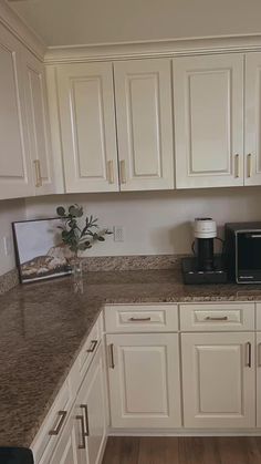 a kitchen with white cabinets and granite counter tops, along with a black microwave oven