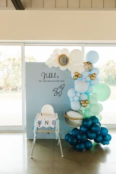 balloons are arranged in front of a backdrop for a baby's first birthday party