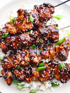 chicken skewers are served over white rice on a plate with chopsticks