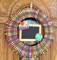 a wreath made out of colored crayons with a chalkboard in the middle