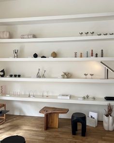 a living room filled with lots of white shelves and wooden flooring next to each other