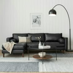 a living room with a black leather couch and coffee table in front of a white wall