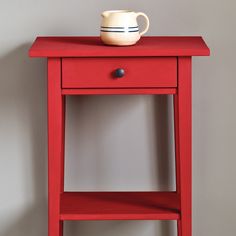 a small red table with a white cup on top