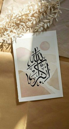 a piece of paper with an arabic calligraphy on it next to a vase filled with flowers