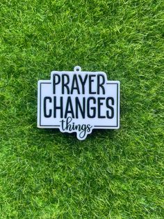 a white and black sign that says prayer changes things on it in the green grass