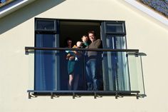 three people are standing on the balcony looking out