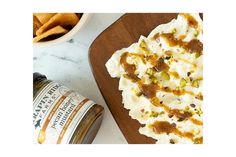 a wooden cutting board topped with food next to a bowl of chips