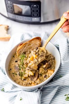 a person holding a wooden spoon in a bowl filled with mushroom and cheese soup next to an instant pressure cooker