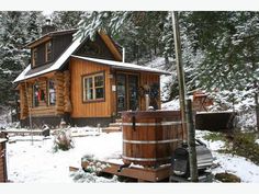 a log cabin with a hot tub in the front yard and snow on the ground