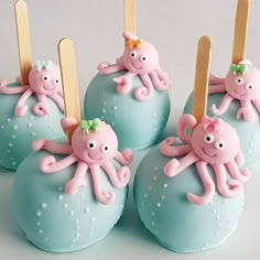 four cake pops decorated with pink and blue fondant octopus on top of each other