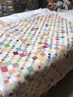 a bed with a quilt on top of it in a room filled with other items