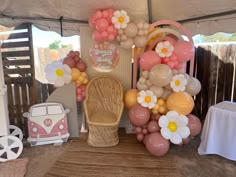 balloons and flowers decorate the back of a chair under a tent at a birthday party