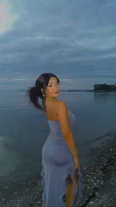 a woman in a blue dress standing on the beach