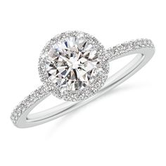 a white gold engagement ring with diamonds on the band and an oval halo setting in the center