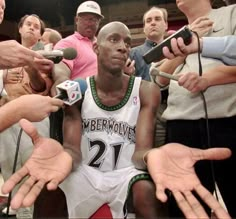 the basketball player is surrounded by reporters and microphones