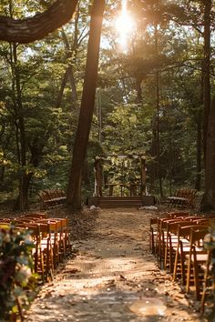 an outdoor ceremony set up in the woods with wooden chairs and flowers on the aisle