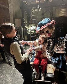 two women and a child dressed up in costumes on a motorcycle with other people standing around