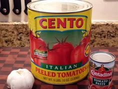 a can of tomato paste next to some tomatoes and garlic on a kitchen counter top