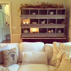 a couch with pillows and candles on top of it in front of a book shelf