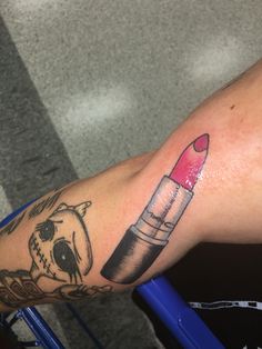 a person with a tattoo on their arm holding a red lipstick