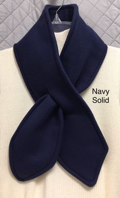 the navy blue scarf is folded on top of a white sweater