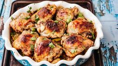 a dish filled with chicken and garnishes on top of a wooden table