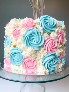 a cake with blue, pink and white frosting flowers on a glass platter