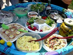 a table filled with lots of food on top of a blue tray covered in plastic