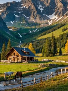 two horses drinking water from a small stream in front of a cabin with mountains in the background