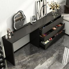 a black and white desk with drawers in the corner next to a mirror, wine rack, and vase