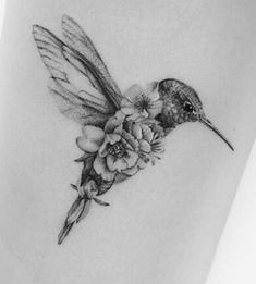 a small hummingbird with flowers on its back leg tattoo by the talented artist in progress