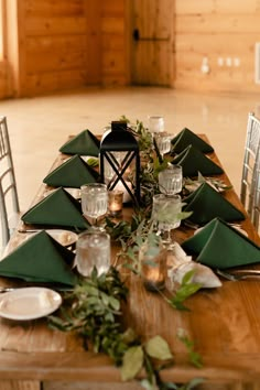 a wooden table topped with green napkins and place settings