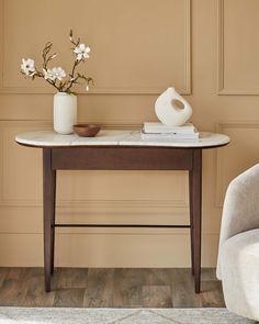 a table with flowers and a vase on it next to a chair in a room