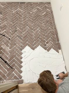 a man laying on the floor next to a wall with a brick pattern painted on it