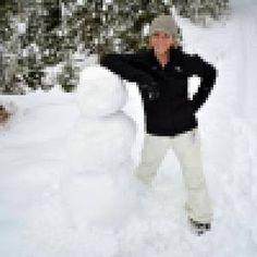 a woman standing in the snow next to a large snowman with her hands on her head