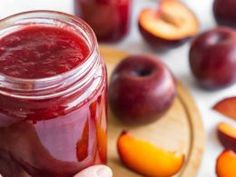 a person holding a jar filled with liquid next to sliced peaches