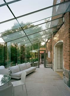 a living room filled with white furniture under a glass covered roof over an outdoor patio