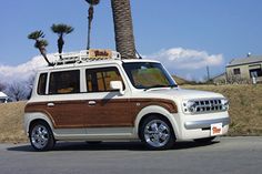 a white and brown vehicle parked on the side of a road next to a palm tree