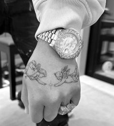 a person with a wrist tattoo holding onto a watch