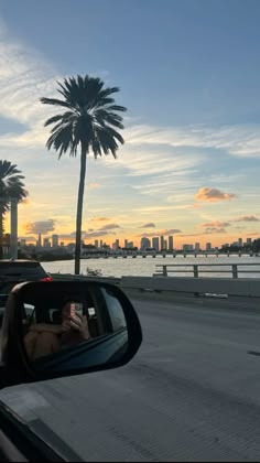 a person taking a selfie in the side mirror of a car as the sun sets